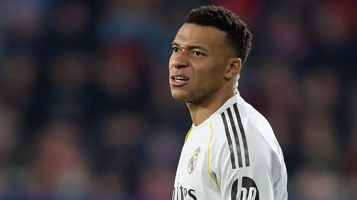 Soccer player in a white Real Madrid jersey looking to his right during a match.